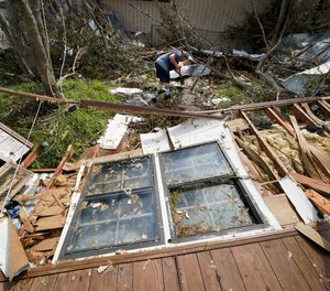Bradley Beard digs as he searches in vain for his water shutoff valve, next to his heavily damaged home and the destroyed trailer home of his daughter in Hackberry, La., in the aftermath of Hurricane Laura, Saturday, Aug. 29, 2020.
