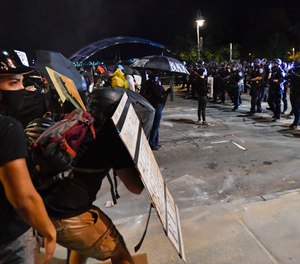 Demonstrators clash with police officers a block from the Public Safety Building in Rochester, N.Y., Friday, Sept. 4, 2020, after a rally and march protesting the death of Daniel Prude. (AP Photo/Adrian Kraus)