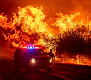 Flames lick above vehicles on Highway 162 as the Bear Fire burns in Oroville, Calif., on Wednesday, Sept. 9, 2020. The Bear Fire has exploded in size, killing three and threatening the community of Paradise, which was devastated by the 2018 Camp Fire.