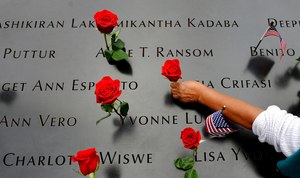 In this Sept. 11, 2014, file photo, a woman places flowers in the inscribed names along the edge of the north pool during memorial observances on the 13th anniversary of the Sept. 11, 2001 terrorist attacks.