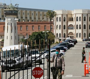 In this July 9, 2020 file photo, a correctional officer closes the main gate at San Quentin State Prison in San Quentin, Calif.