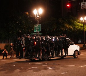 Portland Police line around a van and drive away from protesters rallying at the Mark O. Hatfield United States Courthouse on Saturday, Sept. 26, 2020, in Portland, Ore.