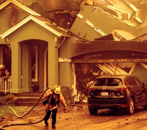 A firefighter carries hose while battling the Glass Fire in the Skyhawk neighborhood of Santa Rosa, Calif., on Monday, Sept. 28, 2020.