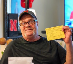 In this undated photo Wally Wolff holds up voter registration paperwork at his home in Omaha, Neb.