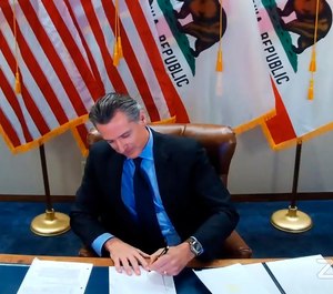 This image shows California Gov. Gavin Newsom signing a bill into law on Sept. 30, 2020, in Sacramento, Calif. (Office of the Governor via AP)