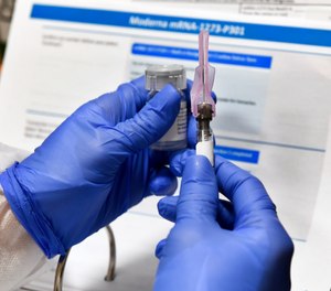In this July 27, 2020, photo, a nurse prepares a shot that is part of a possible COVID-19 vaccine, developed by the National Institutes of Health and Moderna Inc. An Idaho advisory group has proposed a tiered vaccine distribution plan for the state, which puts healthcare workers on the first tier and firefighters, police officers and other essential workers on the second tier. Older adults would receive the next phase of the vaccine, followed by the rest of the population.