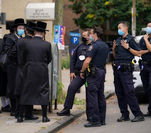 Members of the Orthodox Jewish community speak with NYPD officers, Wednesday, Oct. 7, 2020, in the Borough Park neighborhood of the Brooklyn borough of New York. (AP Photo/John Minchillo)