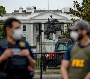 In this June 2, 2020, file photo the White House is visible behind a large security fence as uniformed Secret Service and FBI agents stand on the street in front of Lafayette Park in the morning hours in Washington.