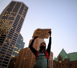 A protester holds a sign while listening to speakers outside Hennepin County Government Center in Minneapolis, Thursday, Oct. 8, 2020. (Aaron Lavinsky/Star Tribune via AP)