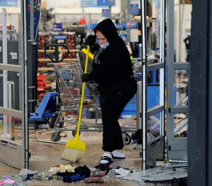 A woman cleans up debris at a Walmart, Wednesday, Oct. 28, 2020, that was damaged in protests in Philadelphia.