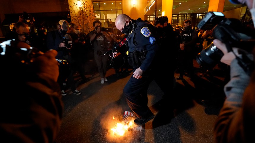 An officer puts out a sign that counter-protesters lit on fire after supporters of President Donald Trump held pro-Trump marches Saturday, Nov. 14, 2020, in Washington. (AP Photo/Julio Cortez)