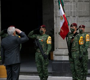 Mexican President Andres Manuel Lopez Obrador salutes the flag during the commemoration of his second anniversary in office, at the National Palace in Mexico City, Tuesday, Dec. 1, 2020.