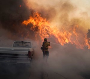 In this Oct. 26, 2020 file photo, a firefighter battles the Silverado Fire in Irvine, Calif. Two firefighters who were critically burned while battling the Silverado Fire were trying to set backfires amid extremely dangerous conditions, a new report from the Orange County Fire Authority states.