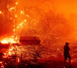 A resident attempts to defend his home as the Bond Fire burns through the Silverado community in Orange County, Calif., on Thursday, Dec. 3, 2020.