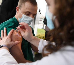 Colleen Teevan, System Pharmacy Clinical Manager at Hartford HealthCare, administers the Pfizer-BioNTech vaccine for COVID-19 to healthcare worker Connor Paleski outside of Hartford Hospital, Monday, Dec. 14, 2020, in Hartford, Conn. The FDA says its preliminary analysis confirmed that a second vaccine, developed by Moderna and the National Institutes of Health, is effective and safe.