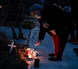 A neighbor lights a candle at a small memorial near the site of the fatal police shooting of Andre Hill on Wednesday, Dec. 23, 2020 on Oberlin Drive in Columbus, Ohio. Columbus fire officials are investigating an apparent delay in the arrival of city paramedics to the scene of the shooting.
