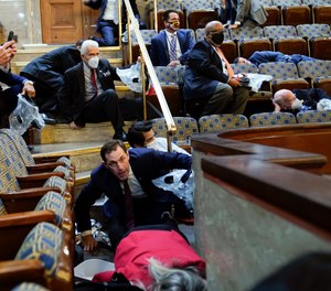 People shelter in the House gallery as protesters try to break into the House Chamber at the U.S. Capitol on Wednesday, Jan. 6, 2021, in Washington.