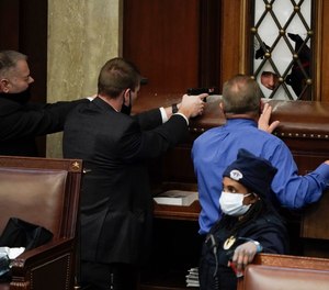 Police with guns drawn watch as protesters try to break into the House Chamber at the U.S. Capitol on Wednesday, Jan. 6, 2021, in Washington.