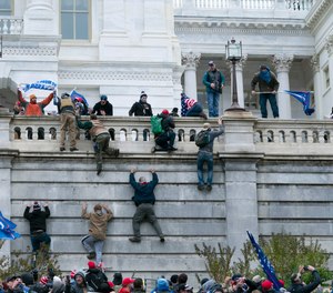 A group of demonstrators climb the west wall of the U.S. Capitol on Wednesday, Jan. 6, 2021. A Sanford firefighter is under investigation for allegedly participating in the mob that breached security and stormed the Capitol building.