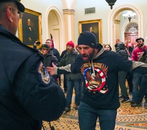 In this Jan. 6, 2021, file photo, Trump supporters gesture to U.S. Capitol Police in the hallway outside of the Senate chamber at the Capitol in Washington.