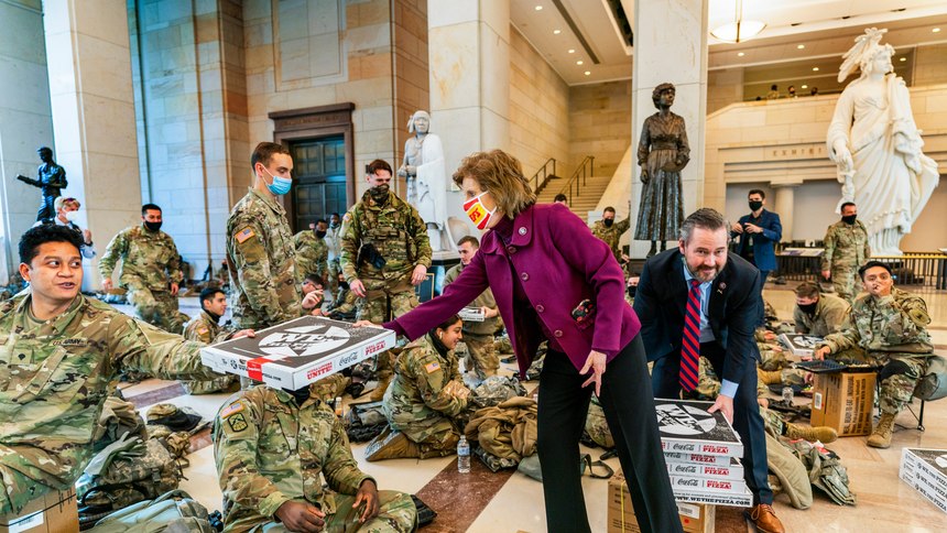 Rep. Vicky Hartzler, R-Mo., and Rep. Michael Waltz, R-Fla., hand pizzas to members of the National Guard gathered at the Capitol Visitor Center, Wednesday, Jan. 13, 2021, in Washington.