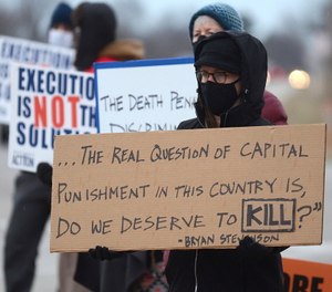 Christina Bollo holds a sign as she protests the execution of Corey Johnson near the Federal Correctional Complex in Terre Haute, Ind.