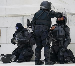 In this Jan. 6, 2021, file photo a police officer has eyes flushed with water after a confrontation with rioters at the Capitol in Washington.