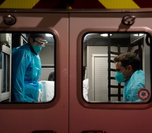 Emergency medical technician Thomas Hoang, left, of Emergency Ambulance Service, and paramedic Trenton Amaro prepare to unload a COVID-19 patient from an ambulance in Placentia, Calif. on Jan. 8, 2021.