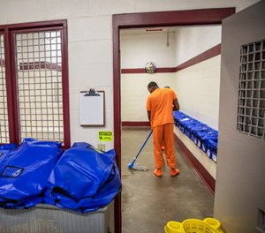 A detainee mops the floor at the intake station at the Stewart Detention Center in Lumpkin, Ga.