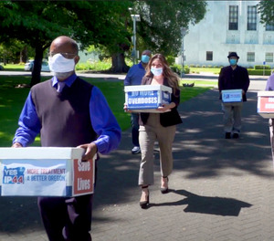 This June 26, 2020 file photo shows volunteers delivering boxes containing signed petitions in favor of the measure to the Oregon Secretary of State's office in Salem.