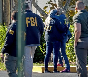 FBI agents console each other as they arrive at the Broward County Medical Examiner's Office in Dania, Fla., after two FBI agents were killed and three wounded while trying to serve a search warrant in Broward County on Tuesday Feb. 2, 2021.