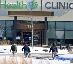 Law enforcement personnel walk toward the Allina Health clinic, Tuesday, Feb. 9, 2021, in Buffalo, Minn.