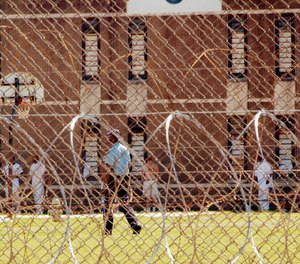 In this Thursday, April 23, 2009, file photo, a correctional officer walks inside a fence past inmates at Donaldson Correctional Facility near Bessemer, Ala.