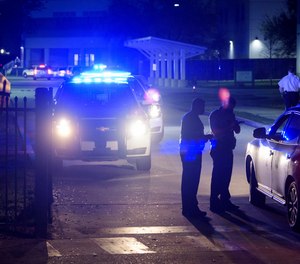 New Orleans police investigate after the fatal shooting of a police officer at George Washington Carver High School where a basketball game was being played, Friday, Feb. 26, 2021, in New Orleans. (Max Becherer/The Times-Picayune/The New Orleans Advocate via AP)