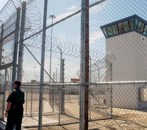 A correctional officer walks near one of two entrances into Kern Valley State Prison, in Delano, Calif.