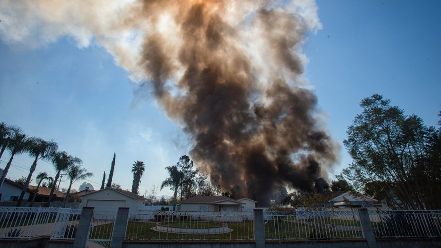 Smoke rises in the background after a fireworks stash exploded in Ontario, Calif.