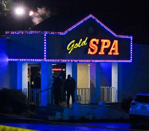 Law enforcement officials confer outside a massage parlor following a shooting on Tuesday, March 16, 2021, in Atlanta. Shootings at two massage parlors in Atlanta and one in the suburbs have left multiple people dead, many of them women of Asian descent, authorities said Tuesday.
