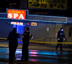 Law enforcement officials confer outside a massage parlor following a shooting on Tuesday, March 16, 2021, in Atlanta. (AP Photo/Brynn Anderson)