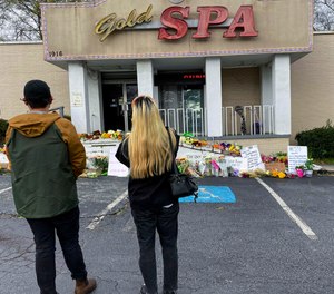Flowers, candles and signs are displayed at a makeshift memorial on Friday, March 19, 2021, in Atlanta.
