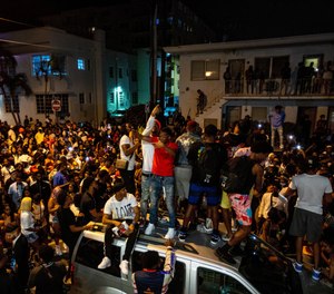 Crowds defiantly gather in the street while a speaker blasts music an hour past curfew in Miami Beach, Fla., on Sunday, March 21, 2021.