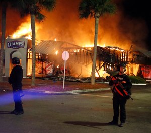 SWAT officers guard firefighters as they respond to the Champs Sports store, Sunday, May 31, 2020 in Tampa. A Florida man was convicted Tuesday, March 30, 2021 of setting fire to the store during unrest that followed protests over the death of George Floyd.