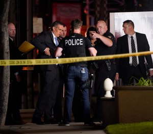 Investigators gather outside an office building where a shooting occurred in Orange, Calif., Wednesday, March 31, 2021.