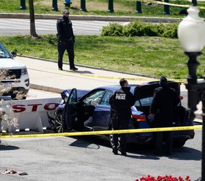 U.S. Capitol Police officers stand near a car that crashed into a barrier on Capitol Hill in Washington, Friday, April 2, 2021.