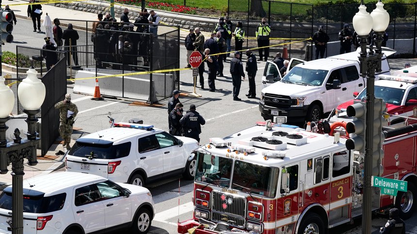 Police and fire officials stand near a car that crashed into a barrier on Capitol Hill in Washington, Friday, April 2, 2021.