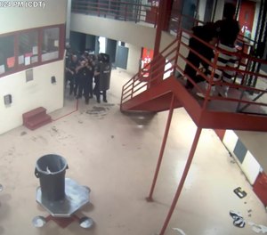 In this Saturday, March 27, 2021, image taken from video released Friday, April 2, 2021, by the Oklahoma City Police Department from the Oklahoma County Detention Center, an officer is attacked by an inmate, upper right, before being shot and killed by police while holding a homemade knife to the officer's neck.