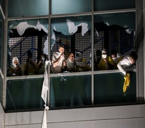 Inmates, from a second cell block, cough and try to breathe through broken windows after officers deploy a chemical irritant at the St. Louis Justice Center.