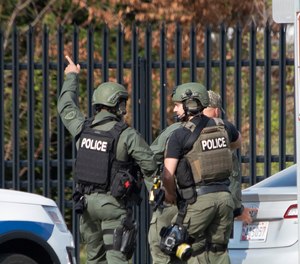 Members of the Frederick Police Department Special Response Team prepare to enter Fort Detrick at the Nallin Farm Gate following a shooting in Riverside Tech Park in Frederick, Md. Authorities say a Navy medic shot two U.S. sailors before fleeing to the Army base, where he was shot and killed.