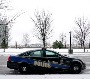 In this Thursday, Feb. 18, 2021, file photo, a Baltimore police cruiser is seen parked near a building while officers check on a call.