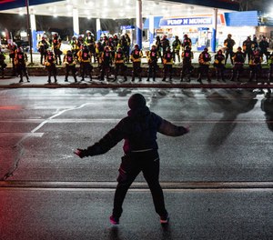 A demonstrator heckles authorities who advanced into a gas station after issuing orders for crowds to disperse during a protest against the police shooting of Daunte Wright, late Monday, April 12, 2021, in Brooklyn Center, Minn.