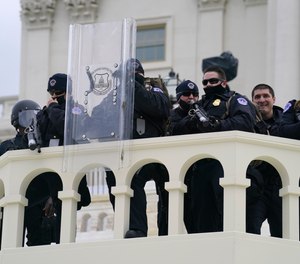 In this Wednesday, Jan. 6, 2021, photo, U.S. Capitol Police officer stand as rioters storm the Capitol in Washington, D.C.